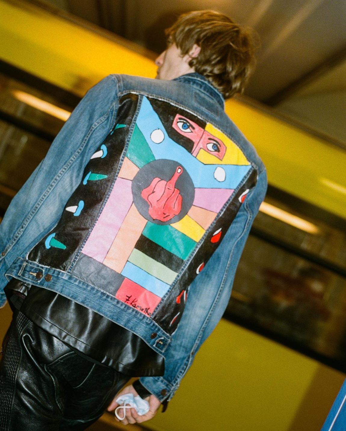 A painted denim jacket by Frantz Lamothe seen from behind on a station platform